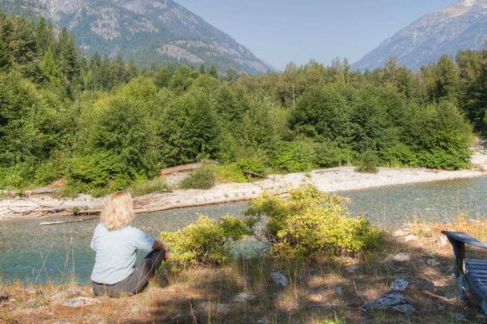 Woman sitting looking at view of lake and trees | North Cascades Lodge at Stehekin